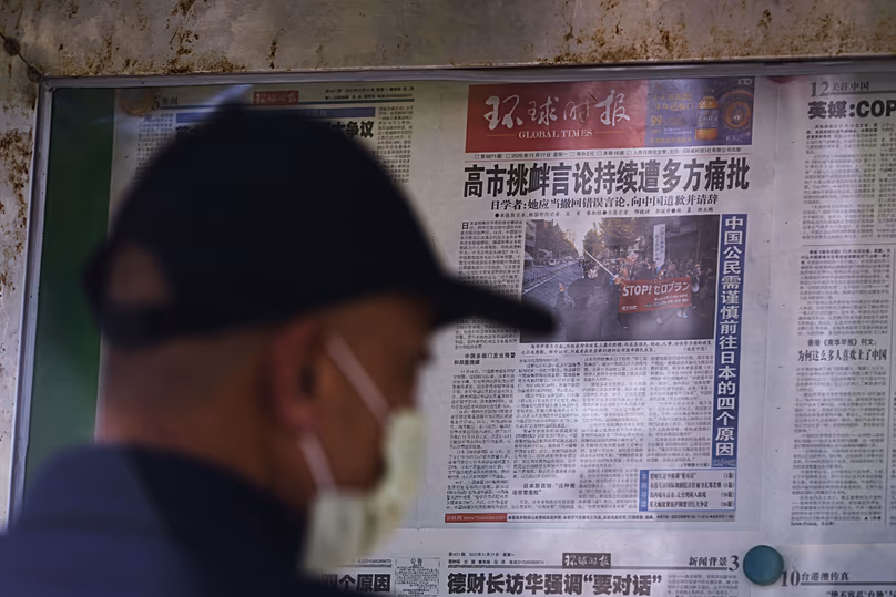 Egy férfi egy pekingi újságostóban helyi újságokat olvas, amelyek Sanae Takaichi japán miniszterelnök közelmúltbeli Tajvannal kapcsolatos kijelentéseiről tudósítanak.