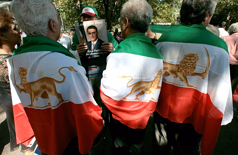 Az iráni-amerikai tüntetők a forradalom előtti birodalmi iráni zászlókba burkolóznak, és kikiáltott "koronahercegük", Reza Pahlavi képeit hordozzák magukkal.