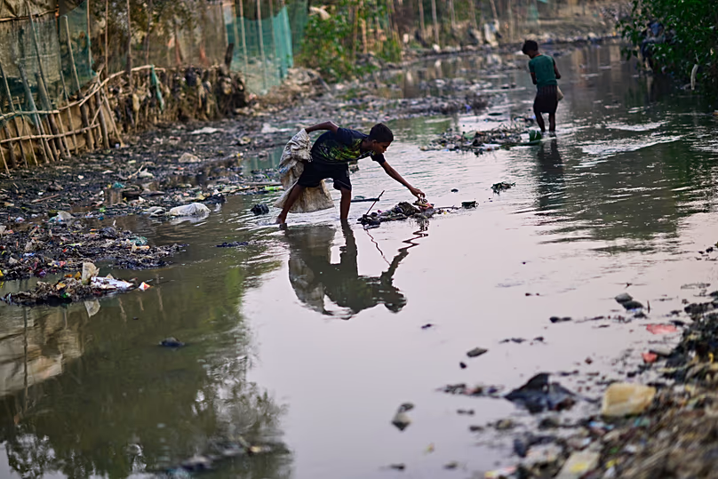 Rohingya menekültek összegyűjtik a műanyag hulladékot a Cox's Bazar-i menekülttáboron belüli vízelvezető csatornából, 2025. november 22.