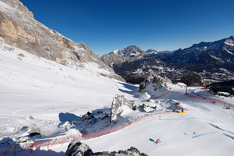 Egy síelőt a Dolomitok tája keretez, amint leszáguld a Tofane pályán az olaszországi Cortina d'Ampezzóban.