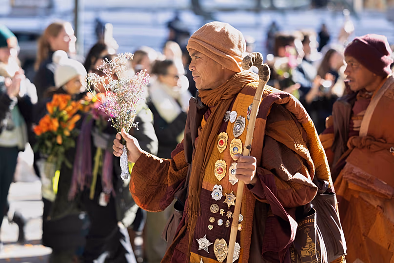 Az egyik tiszteletreméltó buddhista szerzetes virágokat tart kezében, amint békéért sétálnak Richmond belvárosába, 2026. február 2-án, hétfőn.