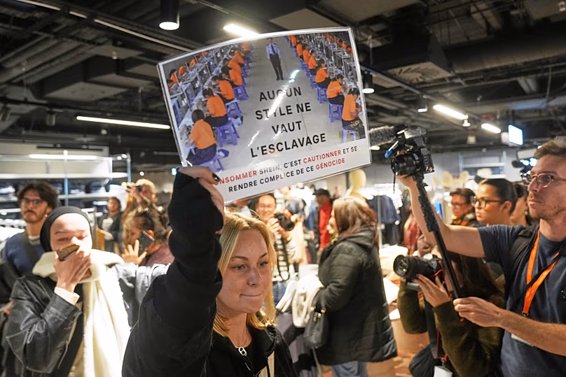 Egy tiltakozó egy plakátot tart a kezében: „Nincs stílus, ami megéri a rabszolgaságot” a BHV áruházban, miközben a Shein 2025. november 5-én, szerdán megnyitja első fizikai üzletét. 