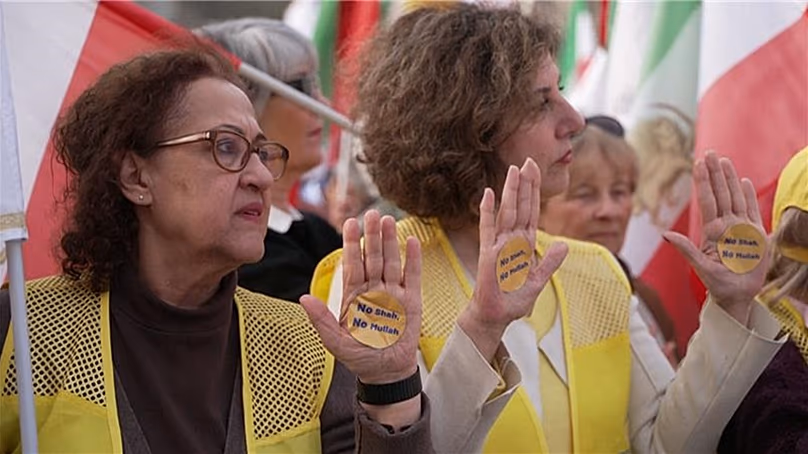 A tenyerüket mutató tiltakozók „No Shah, No Mullah” feliratú matricákkal, Párizs, Franciaország, 2026. március 7.