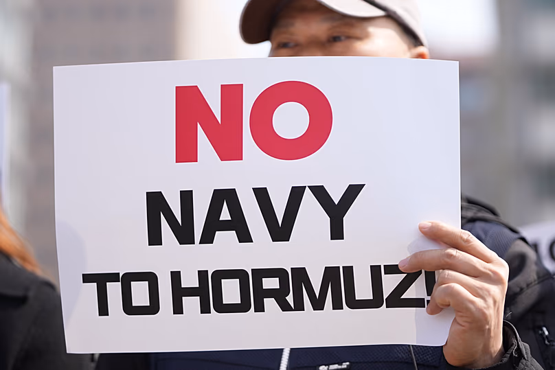 A tiltakozó jelet tart Trump több országhoz intézett követelése ellen, hogy küldjenek hadihajókat a Hormuzi-szoros nyitva tartására az Egyesült Államok nagykövetsége közelében, Dél-Koreában 2026. március 16-án, hétfőn