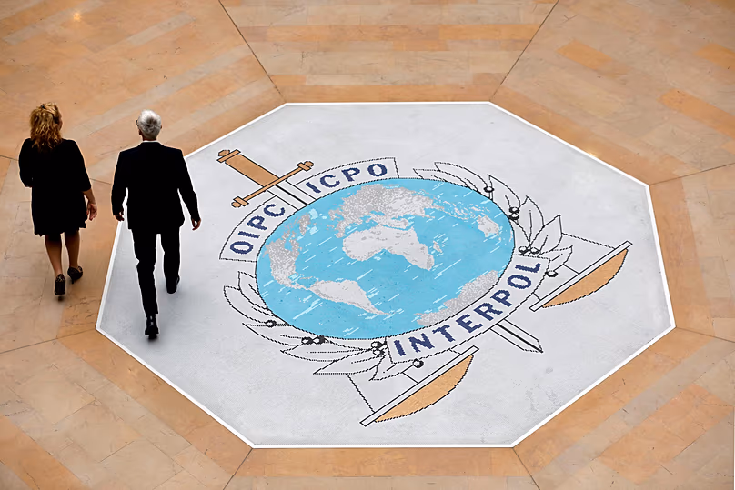 Emberek sétálnak az Interpol logóján a nemzetközi rendőrügynökség lyoni központjában, 2018. november 8.