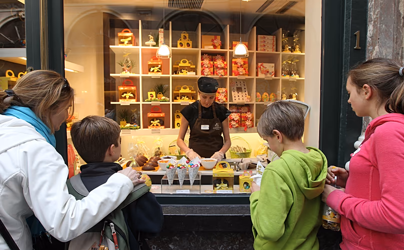 FÁJLÁS: A turisták egy kirakatot néznek, ahol egy nő csokitojásokat díszít húsvétra egy Brüsszel belvárosi csokoládéboltjában 2012. április 6-án, pénteken.