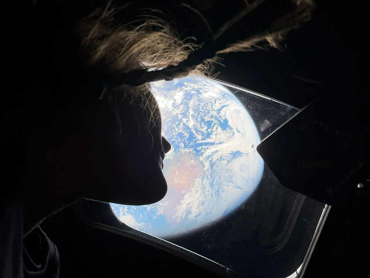 Christina Koch, a NASA űrhajósa és az Artemis II küldetés specialistája az Orion űrszonda egyik fő kabinablakából néz ki, és visszanéz a Földre.