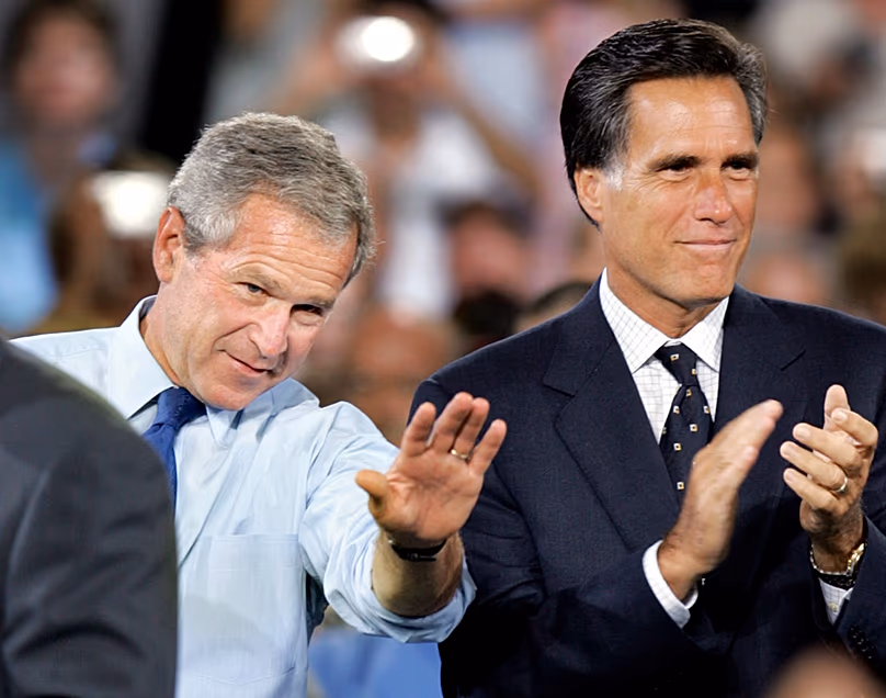 George W. Bush amerikai elnök integet, miközben Mitt Romney massachusettsi kormányzó tapsolt egy kampányrendezvényen Nashuában, New Hampshire-ben, 2004. augusztus 30-án (AP Photo/Steven Senne, File)